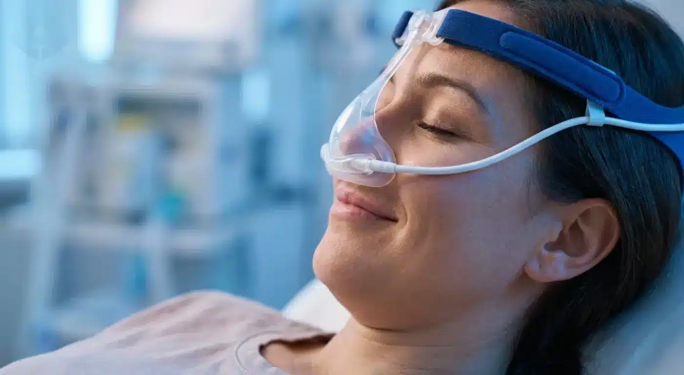 Patient wearing a nitrous oxide mask for mild sedation during a cosmetic dental treatment.
